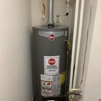 A water heater is in the corner of a room.