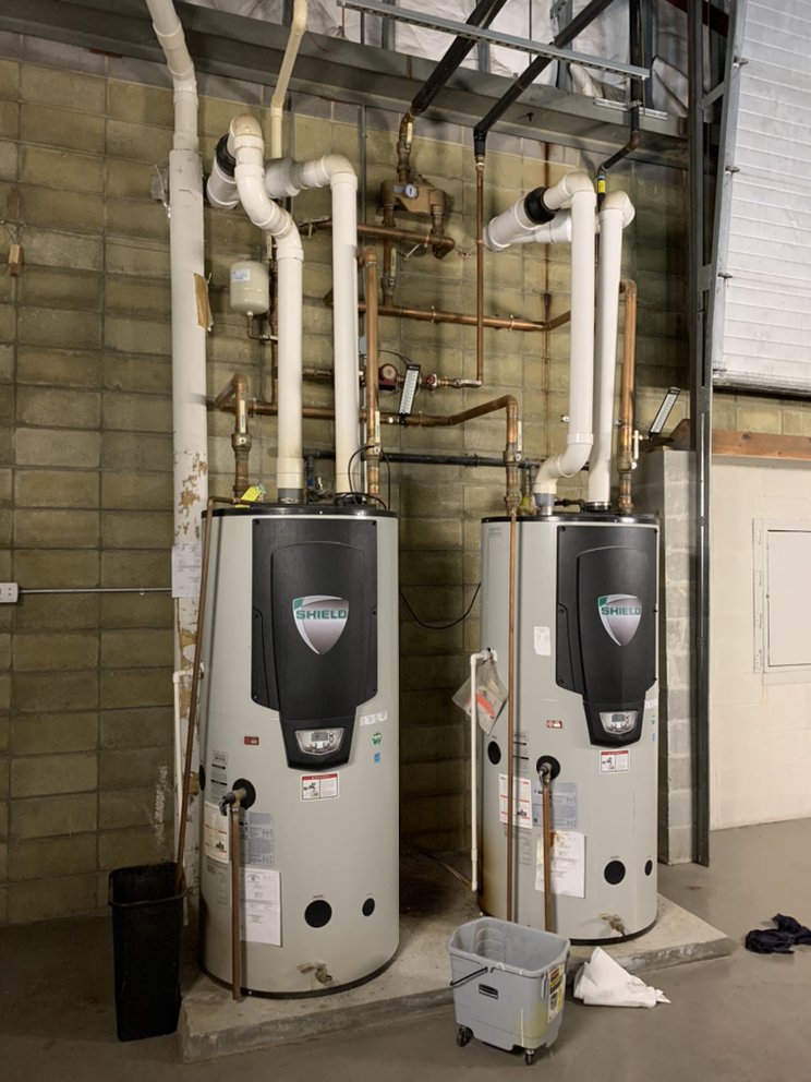 Two gas storage water heaters installed side by side in a utility room
