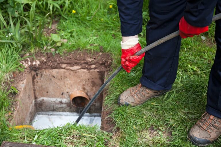 Plumber clearing a blocked outdoor sewer line with a drain cable
