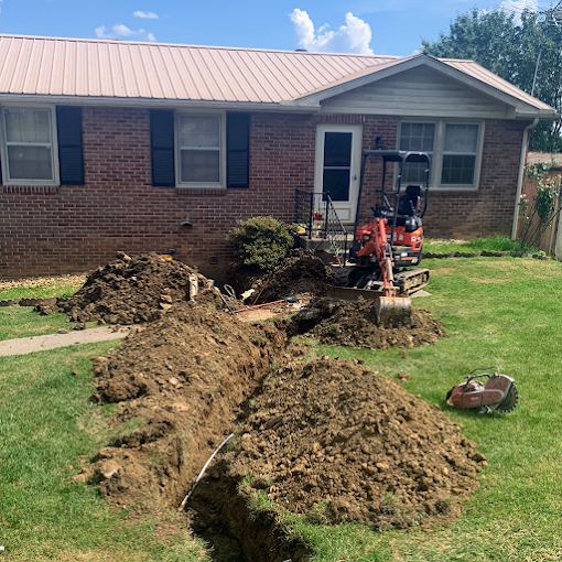 Mini excavator digging a trench across a front lawn for an irrigation line